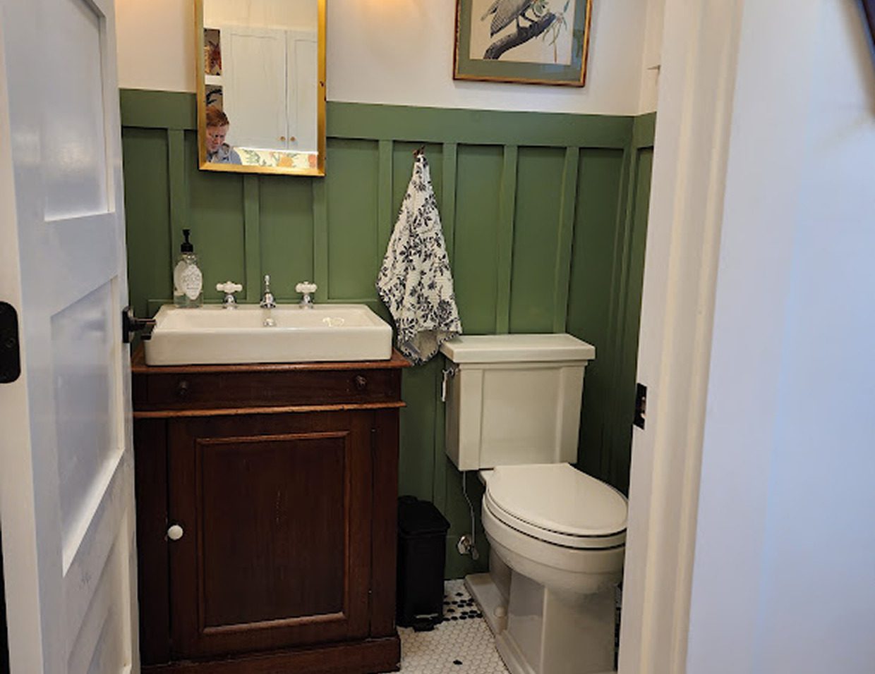 Small bathroom with green wainscoting and sink.