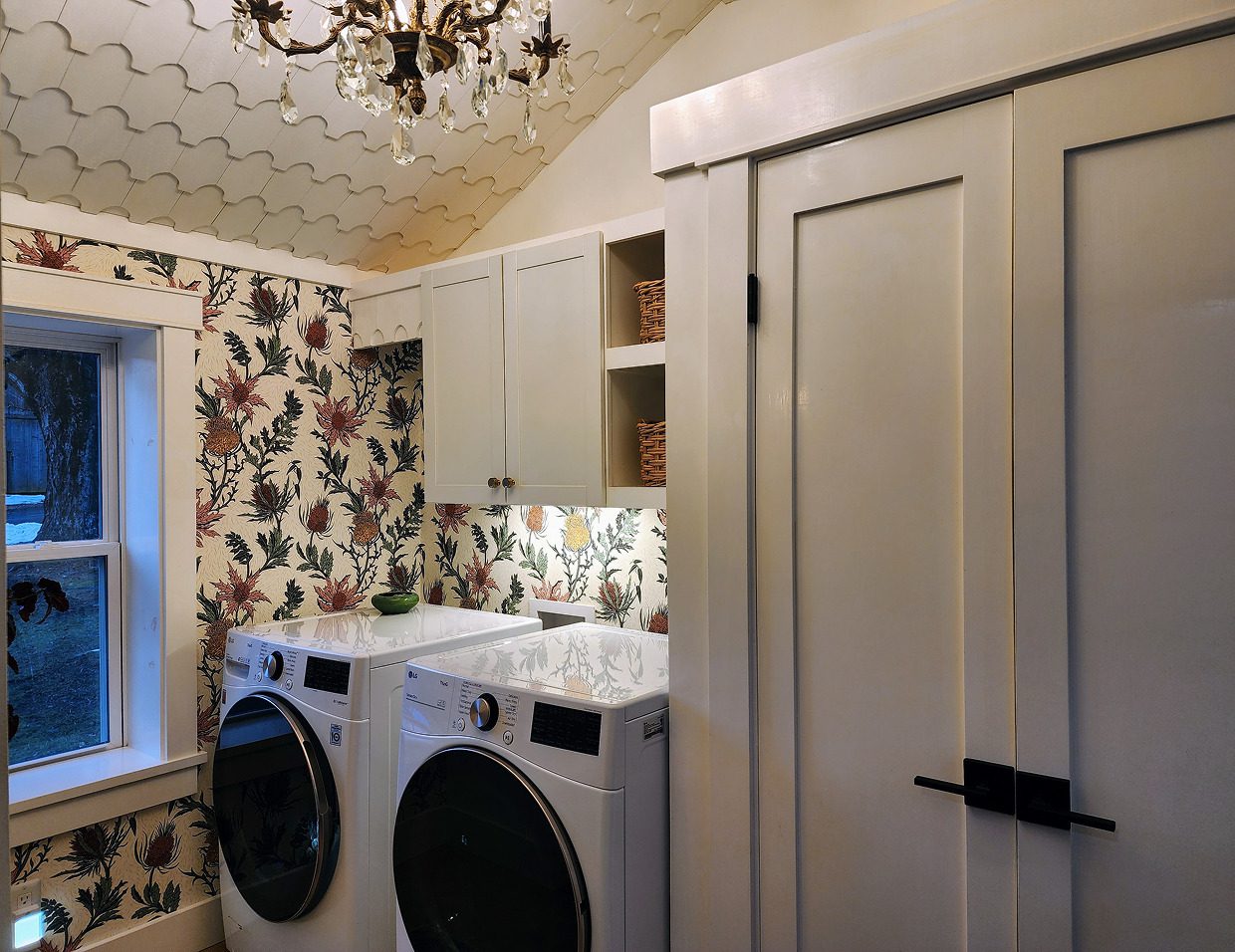 Laundry room with floral wallpaper and chandelier.