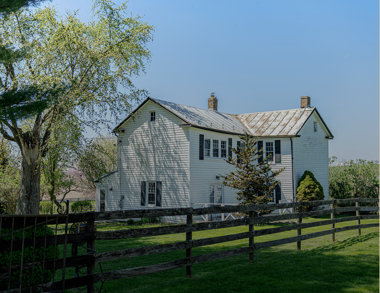 White farmhouse with tree and fence