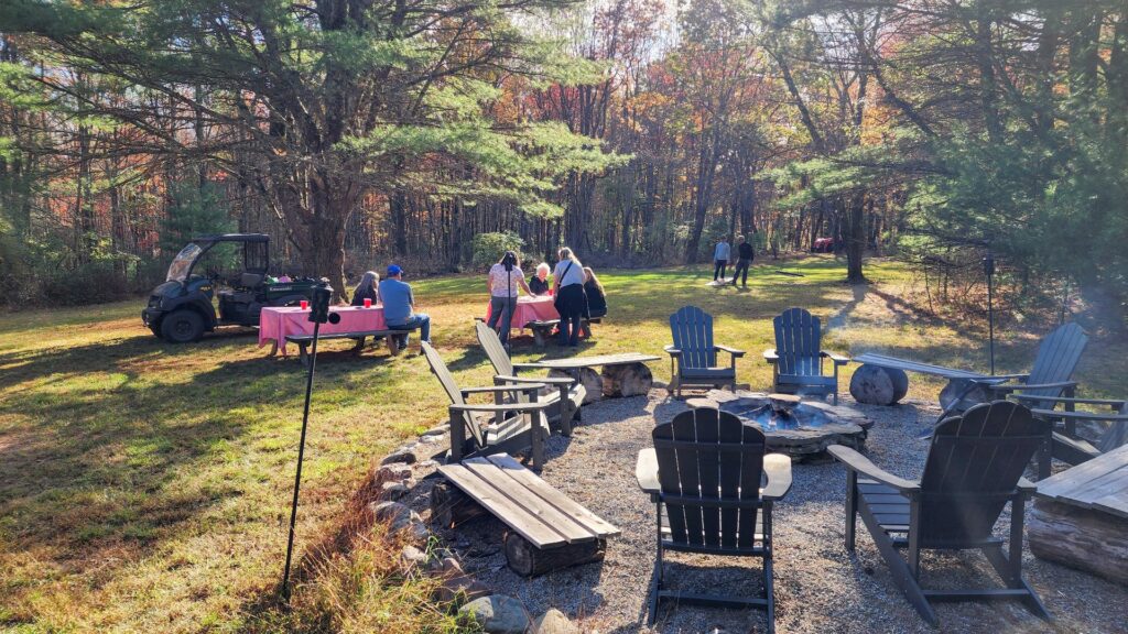 Outdoor gathering with tables and chairs in sunlight.