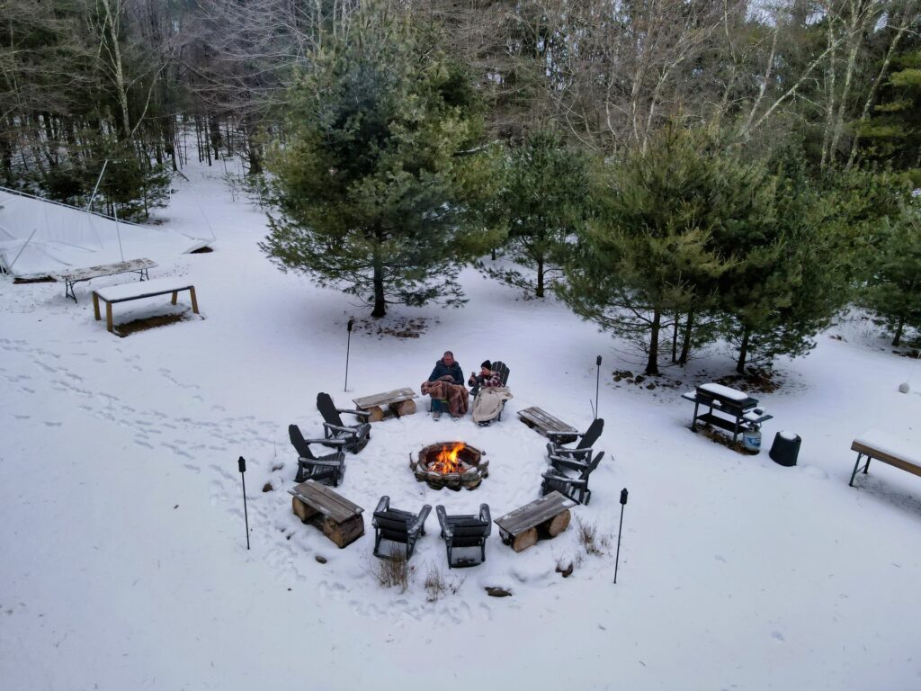 People around a campfire in snowy forest.